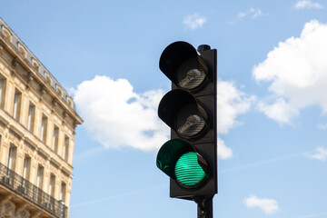 green shining traffic light for car drivers signal next to the street shows that vehicle traffic...