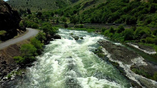 US, Oregon, Maupin, Baxter Rapids, 2025-05-08 - Drone view over the Deschutes River in Spring with a railroad line and green trees in north central Oregon