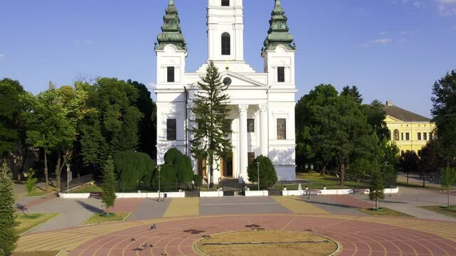 Discover Becej's Stunning Architecture and Lush Greenery Surrounding the Historic Church at Sunrise