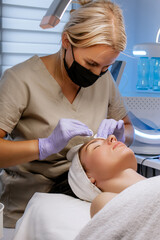 Close-up of professional esthetician performing a facial treatment with cotton pad on woman’s neck during beauty session at a spa, skincare procedure	