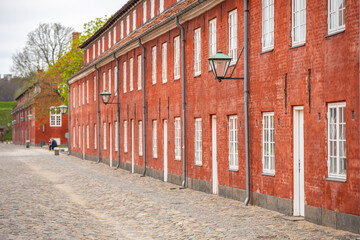 Along a cobblestone path, the vibrant red barracks of Kastellet stand proudly in Copenhagen, Denmark, showcasing their historic architecture and inviting visitors to explore.
