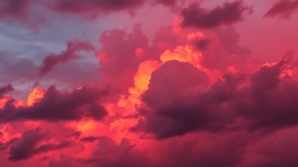 Fototapeta premium Dramatic crimson and red clouds illuminated by the warm glow of the setting sun