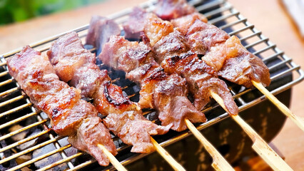 Delicious Beef Satay on Grill: Close-up shot of succulent beef satay skewers grilling on a hot barbecue, smoky aroma and delicious flavors.