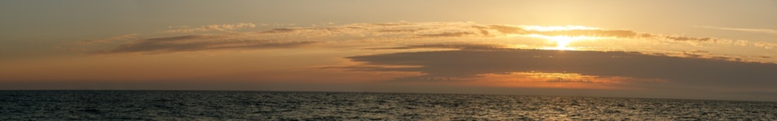 The sun is setting over the ocean, casting a warm glow over the water