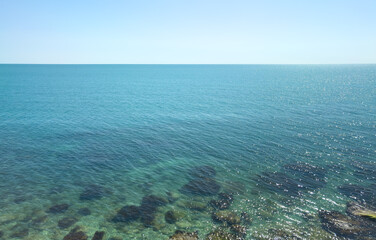Fototapeta premium The ocean is calm and clear, with a few rocks visible in the water