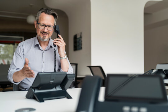Smiling businessman talking on VoIP telephone in office
