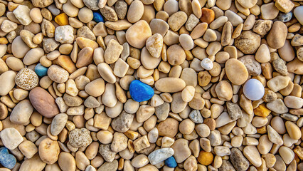 Collection of smooth beach pebbles in varied earth tones with two striking blue and white stones