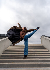 Young athletic woman performs ballet moves on concrete stairs in Stuttgart city