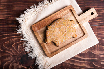 A traditional pig-shaped bread, adorned with sugar crystals, rest on a rustic wooden board