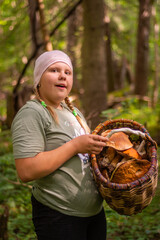 
In autumn, a girl collects mushrooms in the forest.