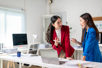 Two women in suits are having a heated discussion in front of a laptop