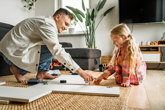 Father and daughter assembling furniture together at home