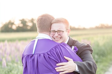 Fototapeta premium Warmly embracing graduates in a field of wildflowers.