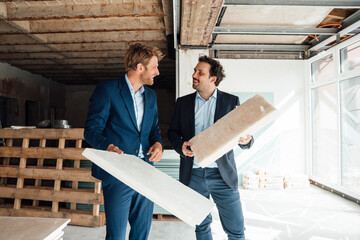 Two businessmen discussing insulation material at a construction site
