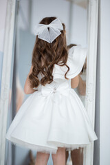 Fototapeta premium a girl with beautiful curls and a long elegant dress with a flower is spinning and dancing