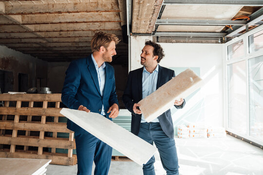 Two businessmen discussing insulation material at a construction site