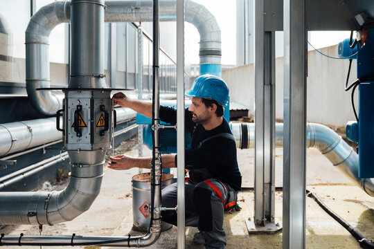 Craftsman working on industrial pipes outdoors wearing a safety helmet