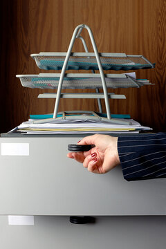 Hand opening a drawer in a vintage office setting with documents and metal trays