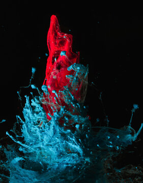 Tornados of red and blue ink mix in clear water creating a dynamic abstract pattern