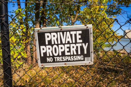 Private property no trespassing sign on a chain link fence in an autumn landscape in the United States