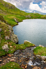 alpine lake in fagaras mountains. dramatic weather in transylvania highland. rippled water surface