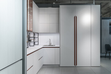 large modern built-in kitchen with lots of upper and lower cabinets, drawers and shelves. light countertop, built-in kitchen appliances, glass doors, steel faucet and sink. luxury kitchen design.