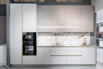 design of large built-in kitchen is white with gold elements, marble countertop, golden faucet and...