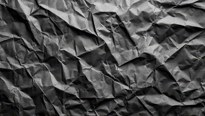 Crumpled dark grey paper texture; deep shadows and folds create a rough, uneven surface