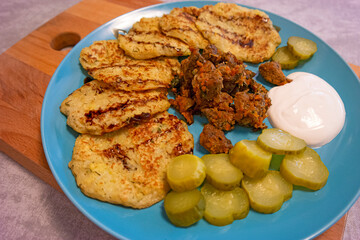 View of Homemade Pancakes From Zucchini with Sour Cream, Baked Pork Meat and Fresh Vegetables On...