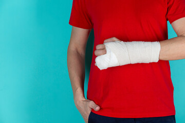 Medical Ideas and Concepts. Closeup of Caucasian Man Damaged Broken Hand In Plaster and Bandaid Isolated on Turquoise Background.