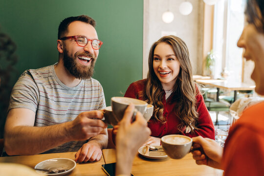 Friends toasting cappuccino, enjoying coffee break at cafe