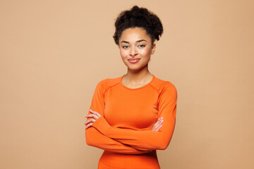 Fototapeta na wymiar Young smiling happy strong fitness trainer instructor sporty woman sportswoman wear orange clothes spend time in home gym look camera isolated on plain beige background. Workout sport fit abs concept.
