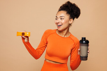 Young fitness trainer woman sportswoman she wear orange clothes spend time in home gym hold eat...