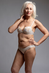 Fototapeta premium Elderly Females Concepts. Closeup of Winsome Thoughtful Calm Positive Mature Confident Caucasian Woman in White Lingerie Posing Over White