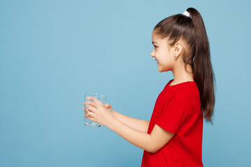 Side view little kid girl 8-9 years old she wear red t-shirt have fun drink water hold glass...