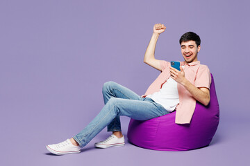 Full body young man wears pink shirt t-shirt casual clothes sit in bag chair do winner gesture...