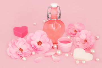 Romantic rose flower spa  feminine beauty treatment products for skincare healing on pink with pearls with heart shape bottle. Soothes eczema, psoriasis, acne.