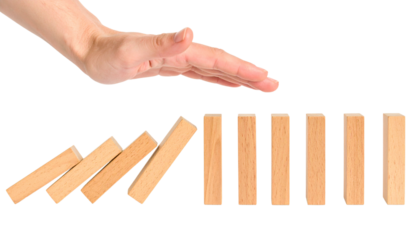 A hand stops falling dominoes, preventing the chain reaction and halting the sequence, against a black background.