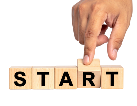 A hand presses a wooden block among others spelling out the word "START".
