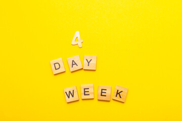 inscription four day week making by wooden cubes on yellow background