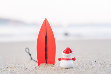 Sandy Christmas Snowman is watching the waves, standing on beautiful beach with a surf board - horizontal version in Patong Beach, Phuket, Thailand