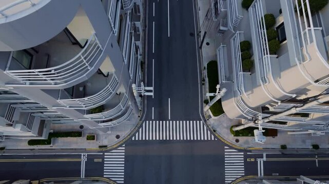 Aerial view of empty city intersection with modern high-rise buildings and marked pedestrian crosswalks

