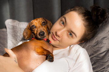 teenage girl cuddles at home with a dachshund dog