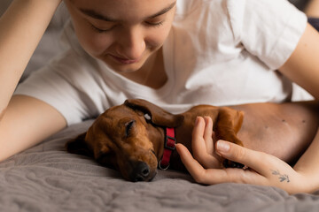 teenage girl cuddles at home with a dachshund dog