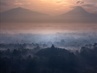 Misty Borobudur temple in the morning with the Merapi, Merbabu and Arjuno mountain in the surroundings. Borodubur is the biggest Buddhist temple in the world that was one of 7 wonders of the worlds.