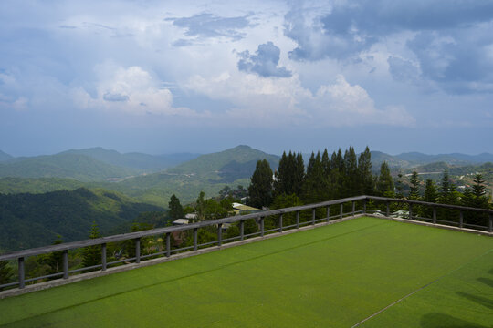 Scenic view of rolling green hills cloudy sky, showcasing vast landscape from balcony. serene atmosphere invites relaxation