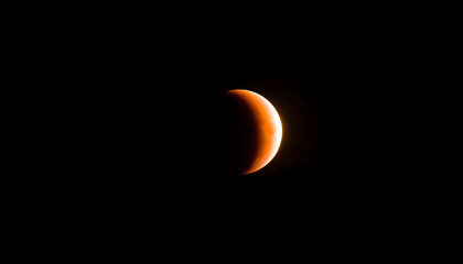 A partially illuminated moon against a dark sky, showcasing a beautiful celestial phenomenon, likely a lunar eclipse