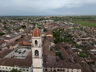 Obraz premium Aerial drone view of Abbazia dei Santi Tommaso e Andrea Apostoli bell tower rising above terra-cotta rooftops in Pontevico, Brescia Italy