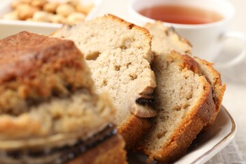 Cut banana bread with nuts and tea on table, closeup