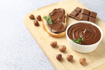 Tasty chocolate spread, toast, hazelnuts and mint on grey textured table, closeup. Space for text